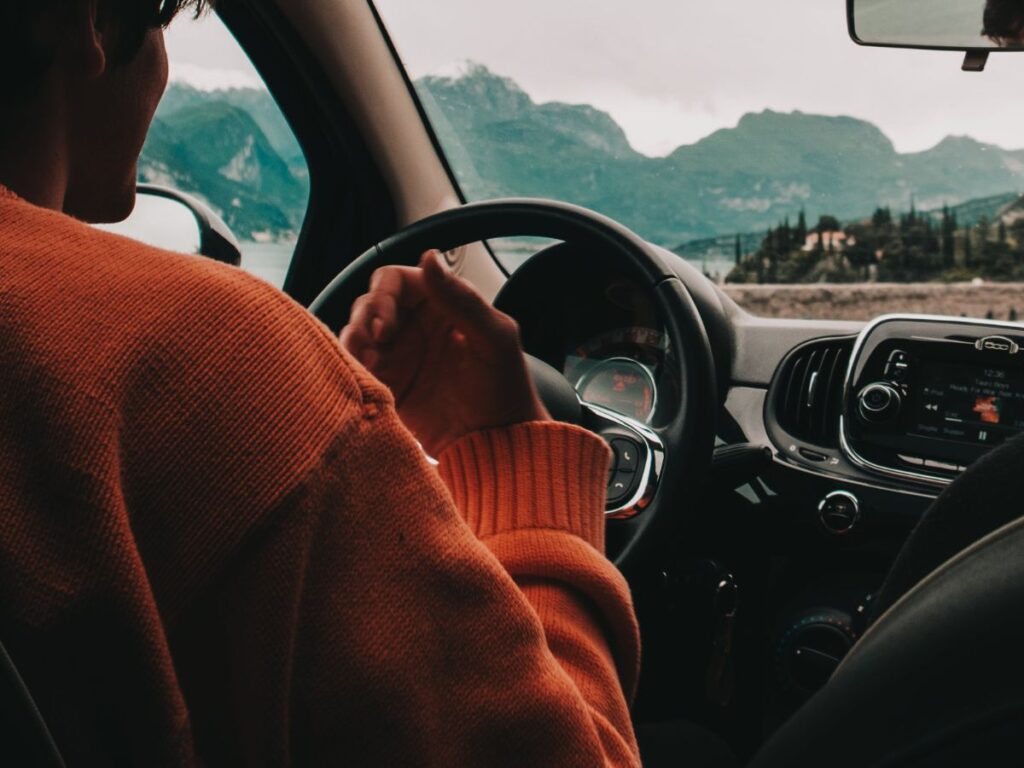 man in driving seat with mountains in bg